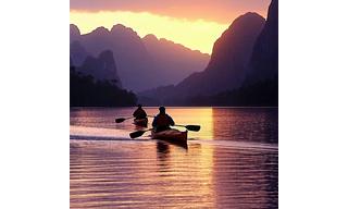 Sunset kayaking on calm water with silhouetted mountains
